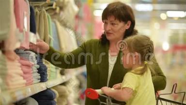 祖母和孙女正在购物中心购买物品。 孙女坐在购物手推车里。